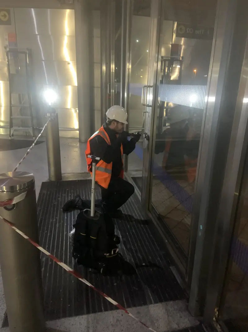 A YY engineer working on a glazed commercial door at night