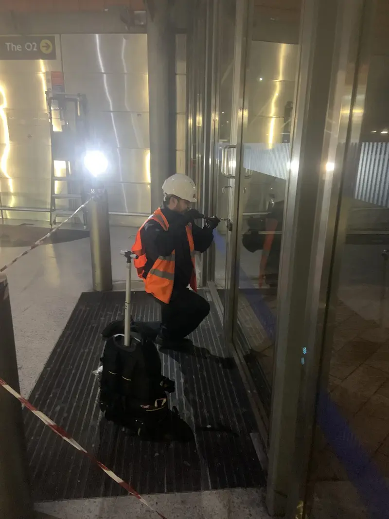 A YY engineer at a glazed door in a station concourse at night
