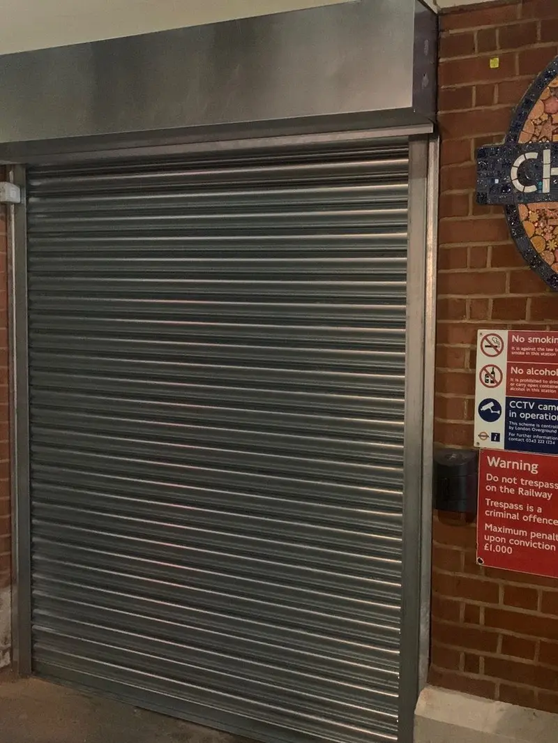 A closed roller shutter at the station entrance.